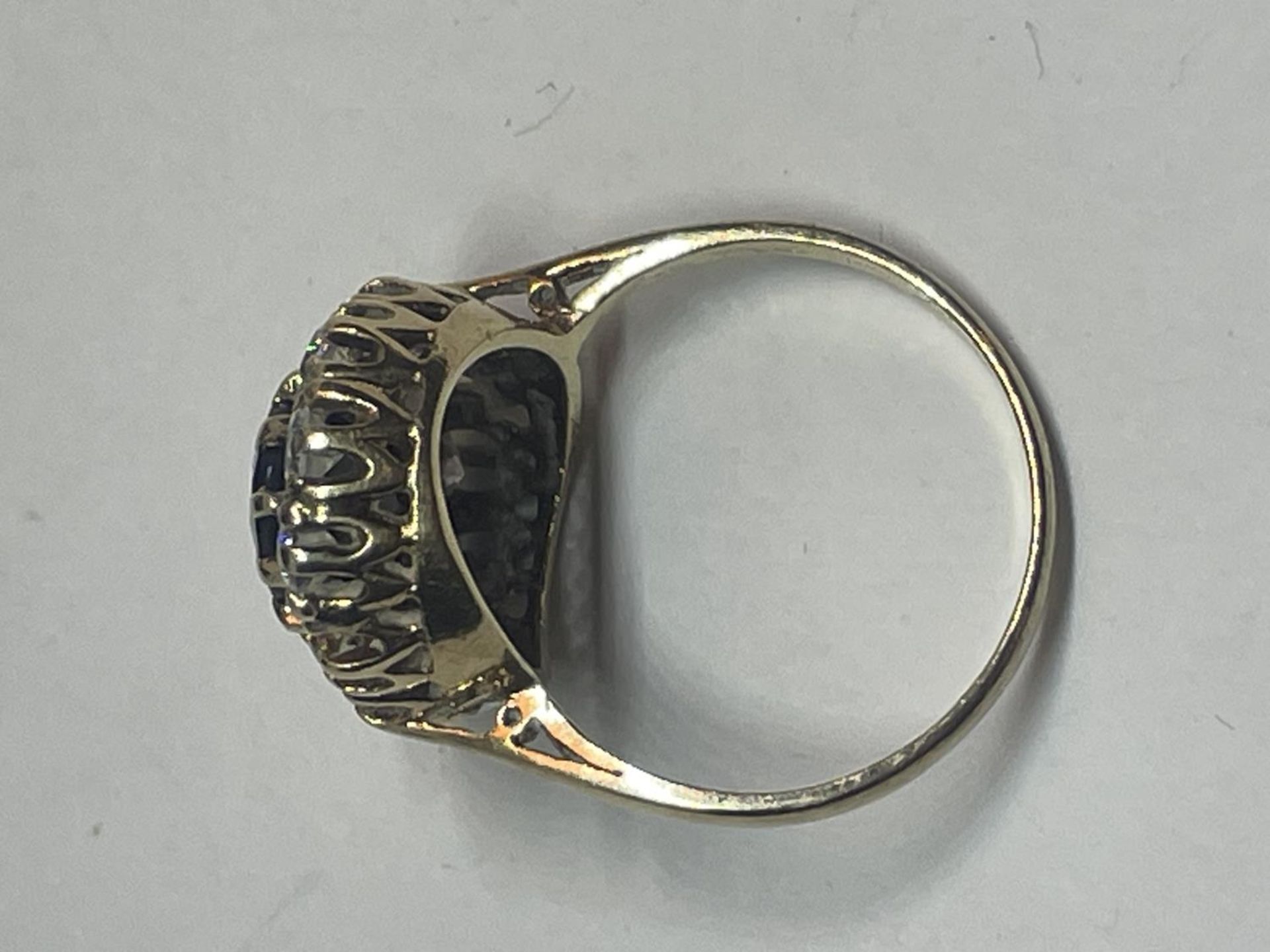 A 9 CARAT GOLD DRESS RING WITH CENTRE BLUE STONE SURROUNDED BY CUBIC ZIRCONIAS SIZE Q IN A - Image 5 of 5