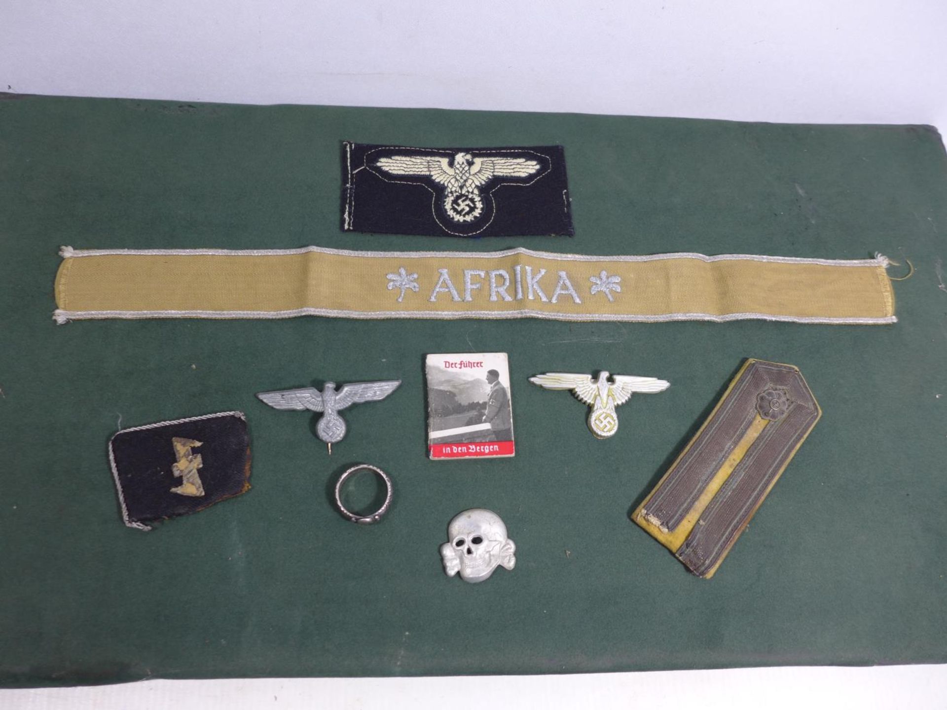 A COLLECTION OF NAZI GERMANY WORLD WAR II BADGES TO INCLUDE AN AFRIKA CORPS TALLY, MINIATURE ADOLF