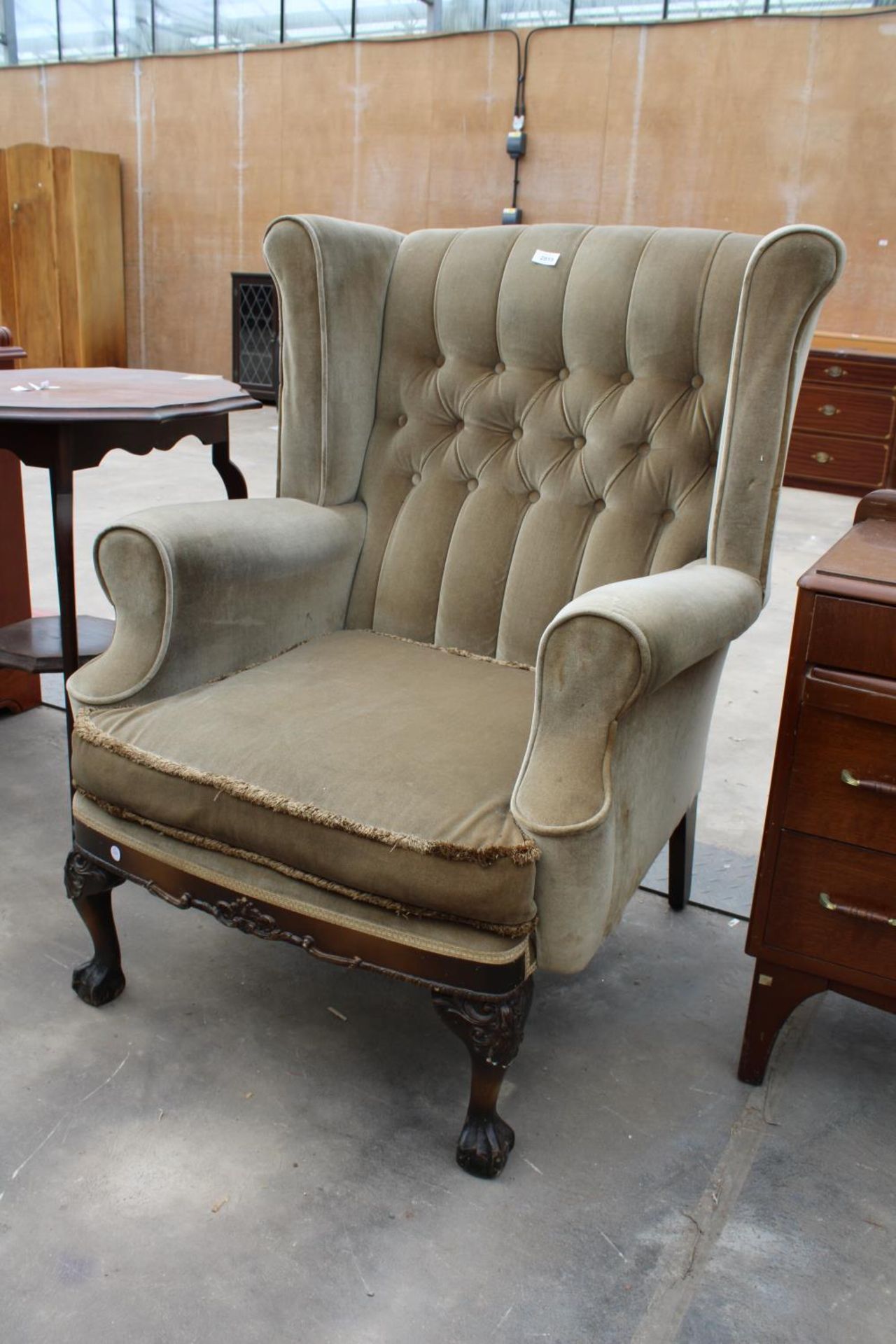 A GEORGIAN STYLE WINGED BUTTON-BACK EASY CHAIR ON FRONT CABRIOLE LEGS WITH CARVED KNEES ON BALL