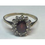 A 9 CARAT GOLD RING WITH A CENTRE GARNET SURROUNDED BY CUBIC ZIRCONIAS SIZE V
