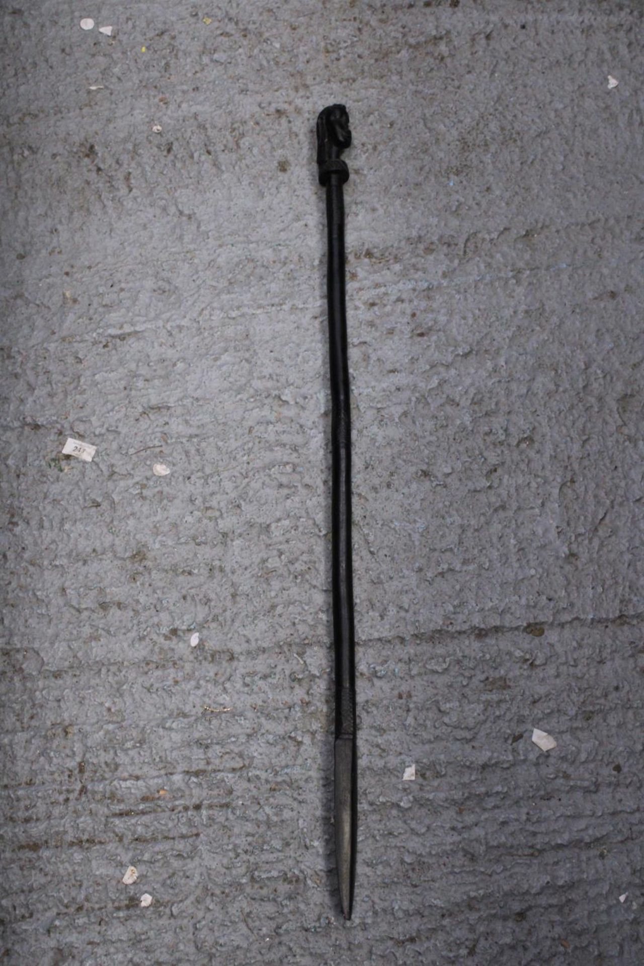 AN ETHNIC AFRICAN BLACK WOODEN SPEAR - WITH CARVED HEAD DECORATION TO THE TOP