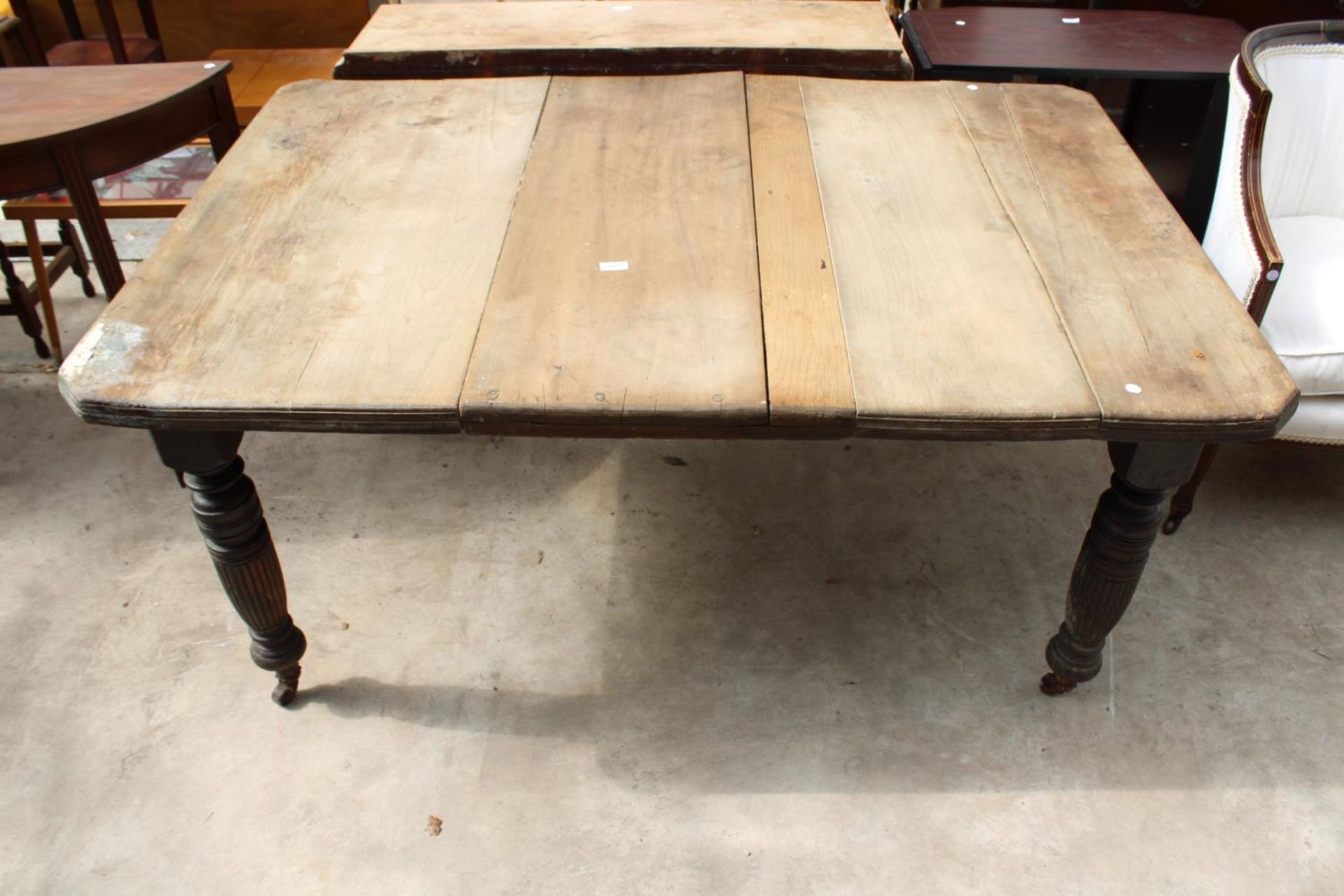 A LATE VICTORIAN SCRUB TOP WIND-OUT DINING TABLE WITH CANTED CORNERS ON TURNED AND FLUTED LEGS