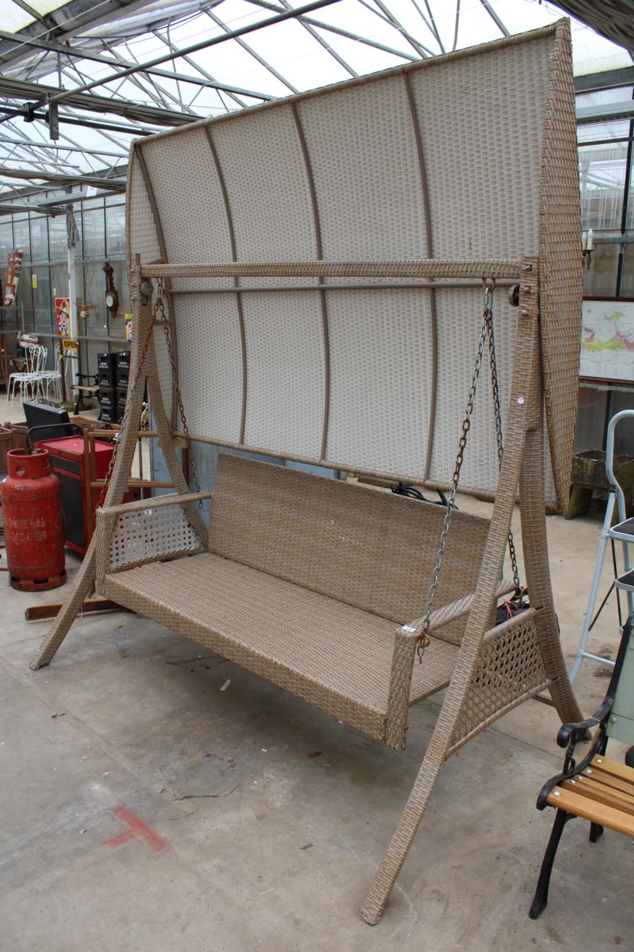 A LARGE THREE SEATER RATTAN SWING SEAT WITH CANOPY