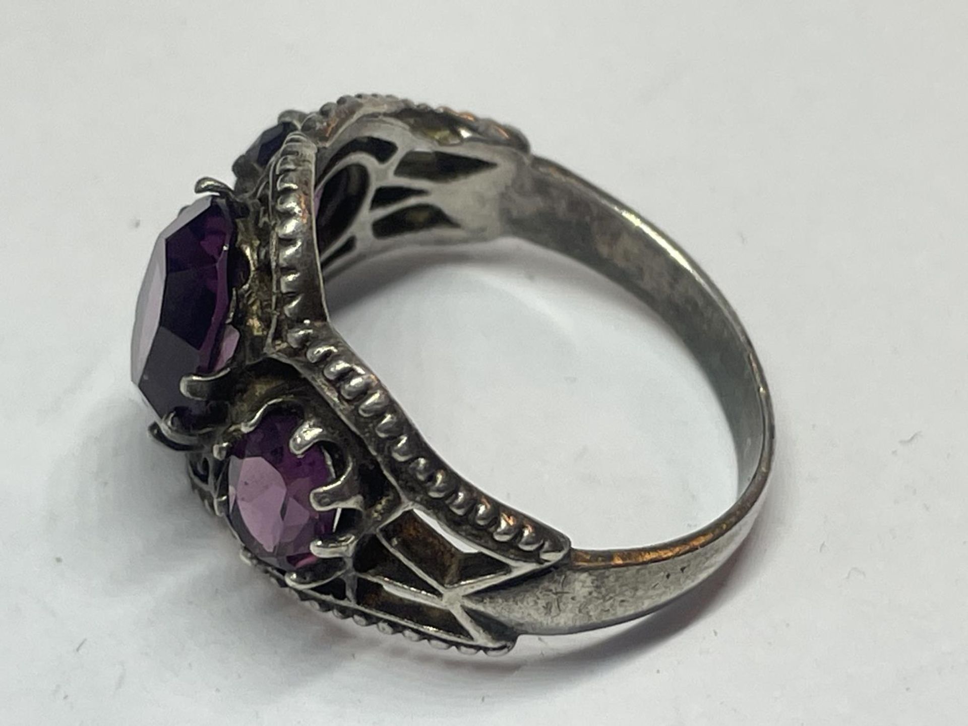 A SILVER RING WITH AMETHYST COLOURED STONES - Image 2 of 3