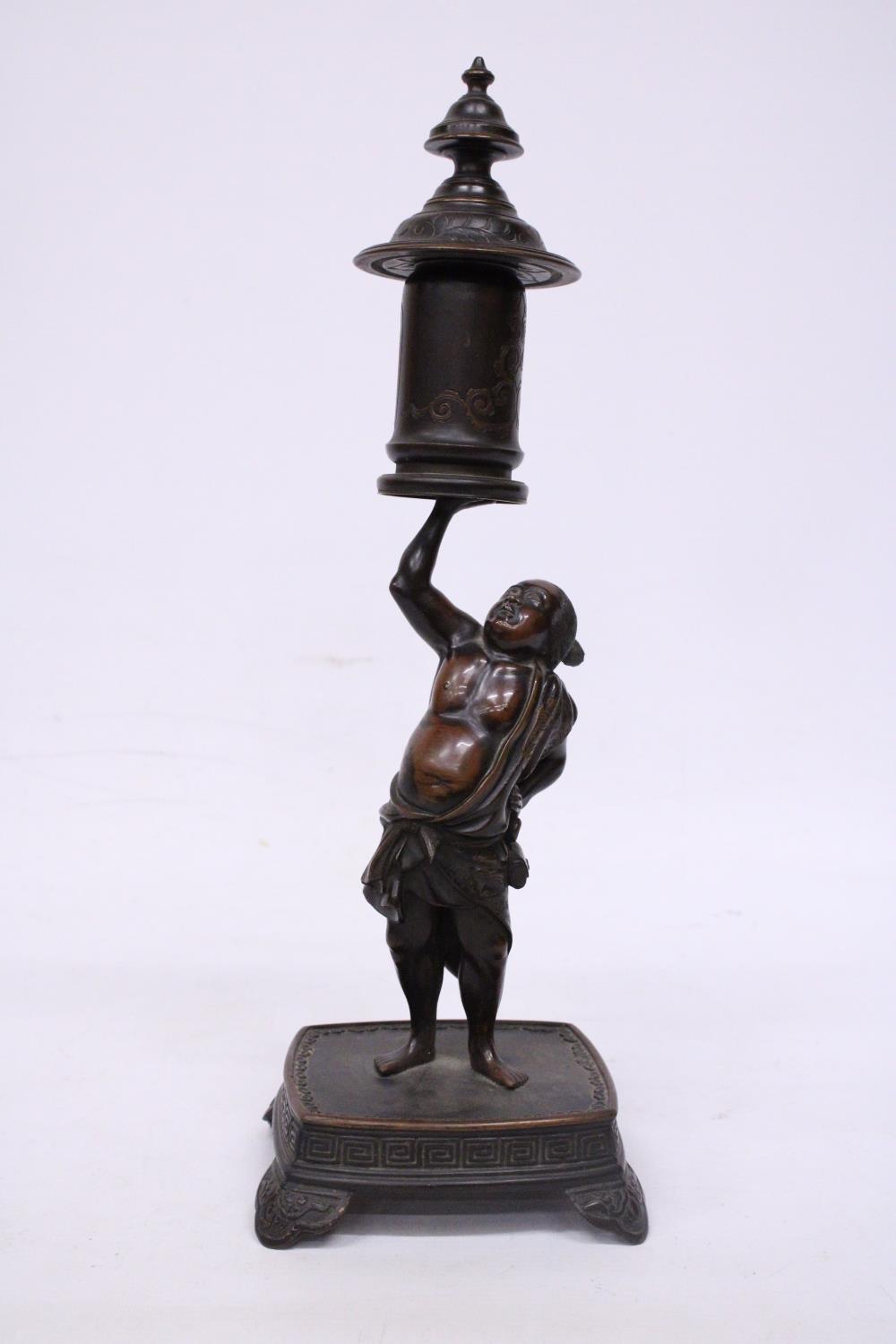 A BRONZE MEIJI PERIOD STATUE OF A FIGURE HOLDING A VASE WITH COVER