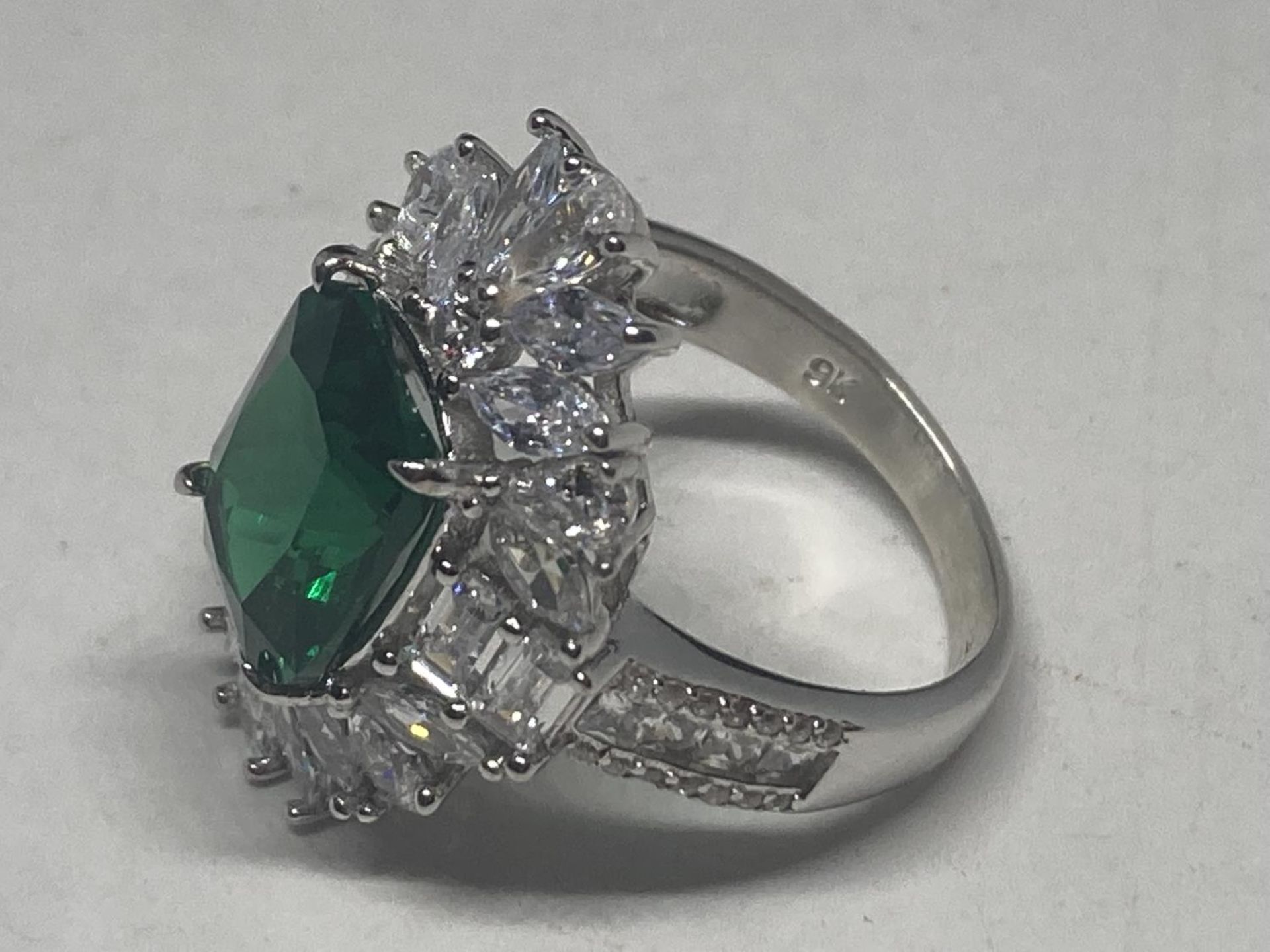 A WHITE METAL RING WITH A LARGE CENTRE LABORATORY GROWN EMERALD SURROUNDED BY CLEAR STONES SIZE S - Image 3 of 8