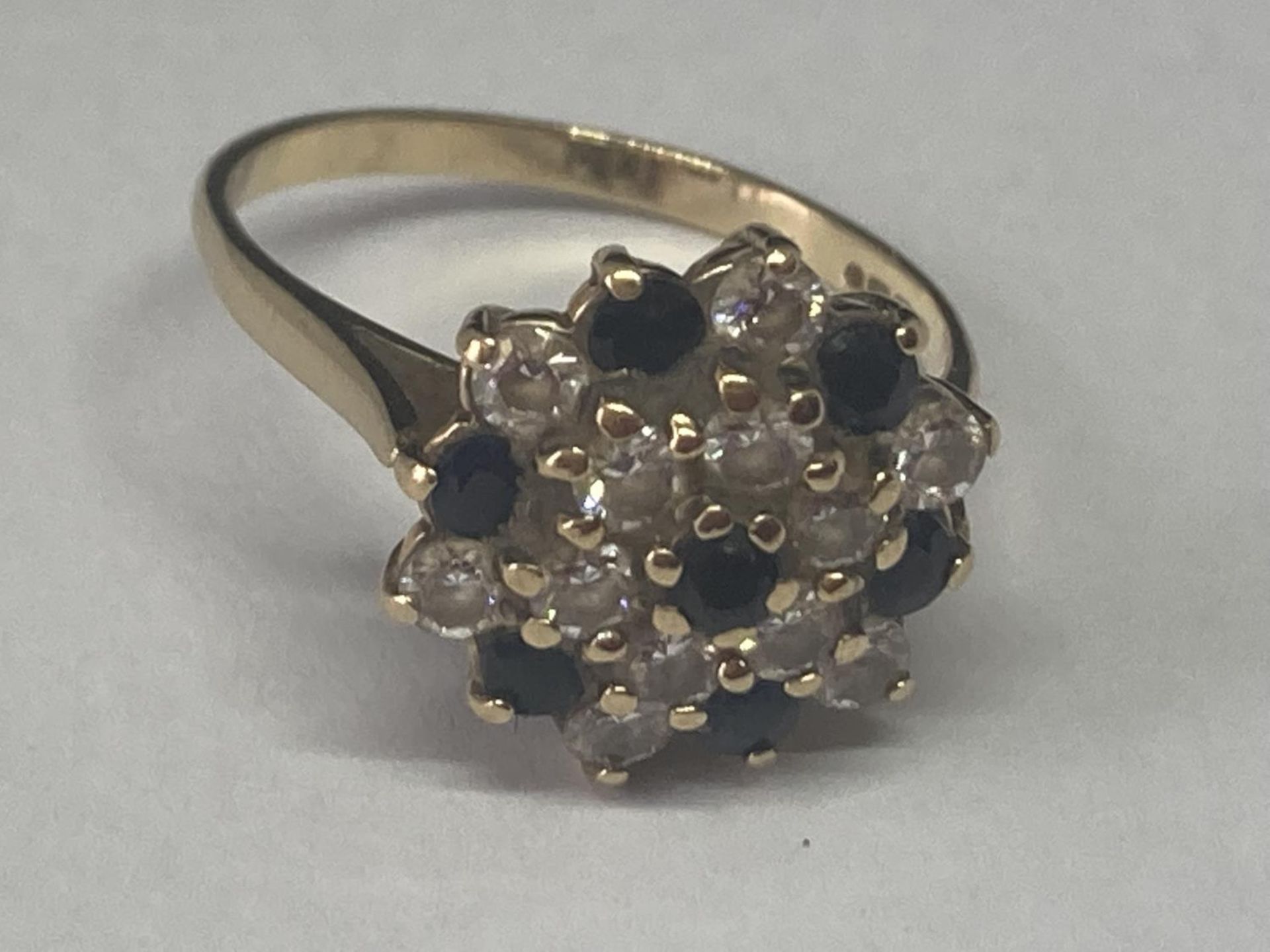 A 9 CARAT GOLD RING WITH SAPPHIRE AND CUBIC ZIRCONIAS IN A CLUSTER DESIGN SIZE M/N