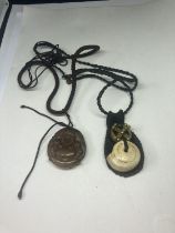 TWO NECKLACES TO INCLUDE A CARVED BUDDHA PENDANT AND A TALISMAN GOOD LUCK AMULET BOTH ON A LEATHER