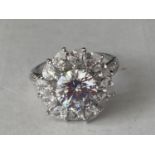 A WHITE METAL RING WITH 3 CARATS OF MOISSANITE IN A FLOWER DESIGN AND ON THE SHOULDERS SIZE P/Q