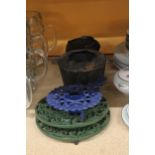 A CAST IRON COOK POT ON STAND PLUS TWO KETTLE STANDS AND CANDLE HOLDER