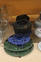 A CAST IRON COOK POT ON STAND PLUS TWO KETTLE STANDS AND CANDLE HOLDER