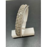 A NEW 9 CARAT WHITE GOLD HINGED BANGLE, SET WITH BRILLIANT AND BAGUETTE CUT DIAMONDS OF TOTAL WEIGHT