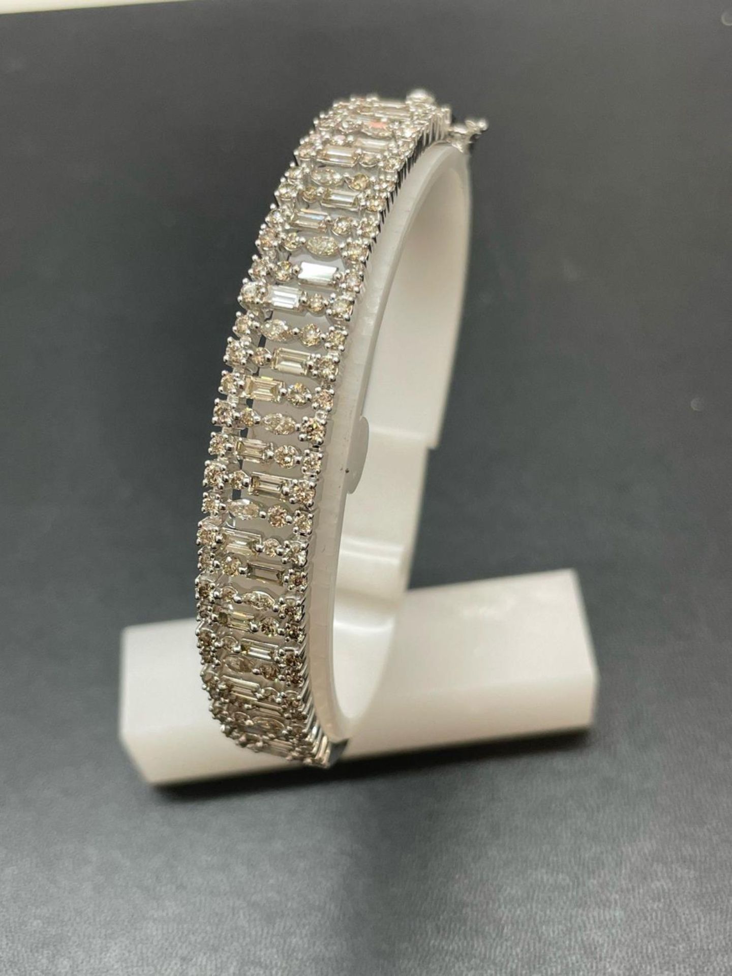 A NEW 9 CARAT WHITE GOLD HINGED BANGLE, SET WITH BRILLIANT AND BAGUETTE CUT DIAMONDS OF TOTAL WEIGHT