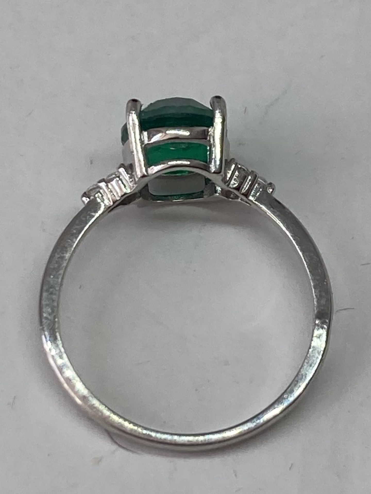 A WHITE METAL RING WITH AN OVAL LABORATORY EMERALD WITH THREE CLEAR STONES TO EACH SIDE SIZE Q/R - Image 5 of 6