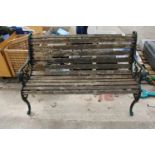 A WOODEN SLATTED GARDEN BENCH WITH DECORATIVE CAST BENCH ENDS