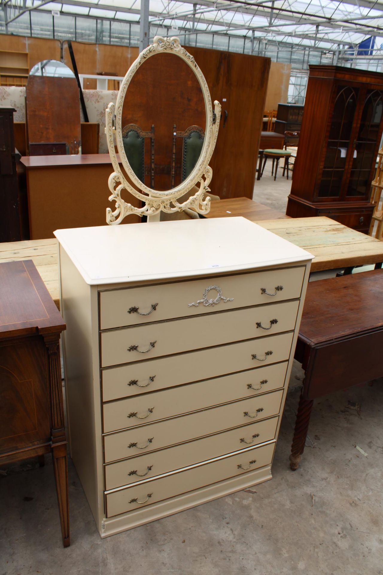 A MODERN CREAM AND GILT DRESSING CHEST WITH SEVEN DRAWERS AND SWING MIRROR, 31" WIDE