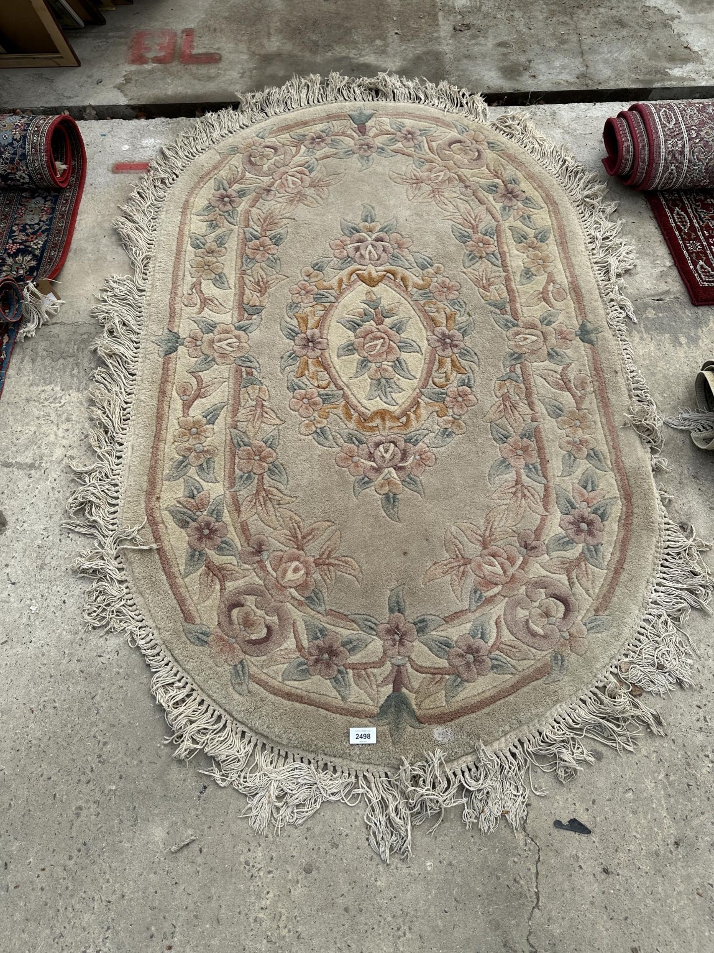 AN OVAL PEACH PATTERNED FRINGED RUG