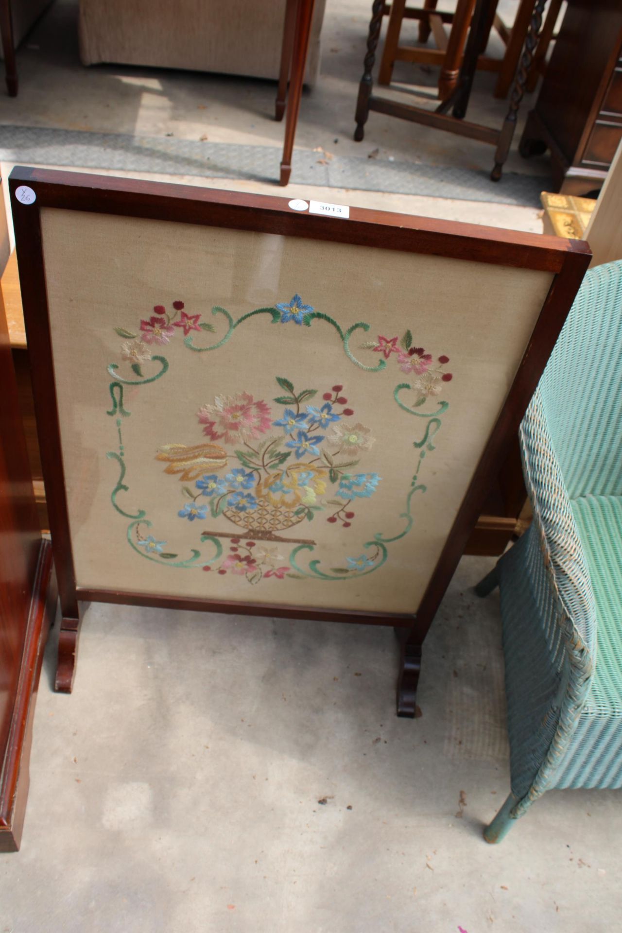 AN EDWARDIAN MAHOGANY FIRESCREEN WITH FLORAL SILKWORK DECORATION