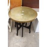 A BRASS 23" DIAMETER INDIAN COFFEE TABLE ON EBONISED FOLDING BASE
