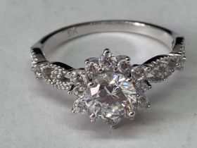 A WHITE METAL RING WITH ONE CARAT OF MOISSANITE IN A CLUSTER DESIGN AND ON THE DECORATIVE
