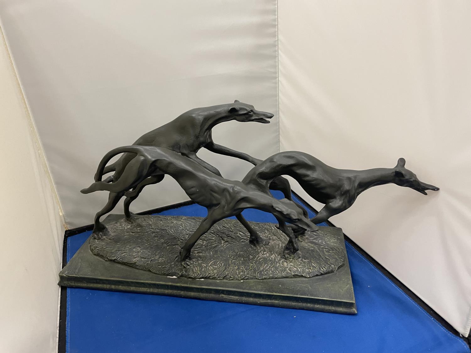 A LARGE RESIN SCULPTURE OF THREE GREYHOUNDS RUNNING ON A BASE LENGTH 38CM