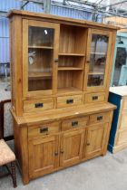 A OAK TWO DOOR BOOKCASE ON BASE, ENCLOSING SIX DRAWERS AND THREE CUPBOARDS, 55" WIDE