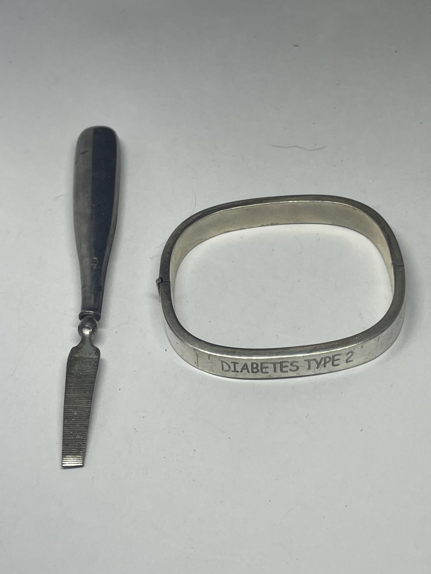 A SILVER BANGLE AND A SILVER HANDLED NAIL FILE