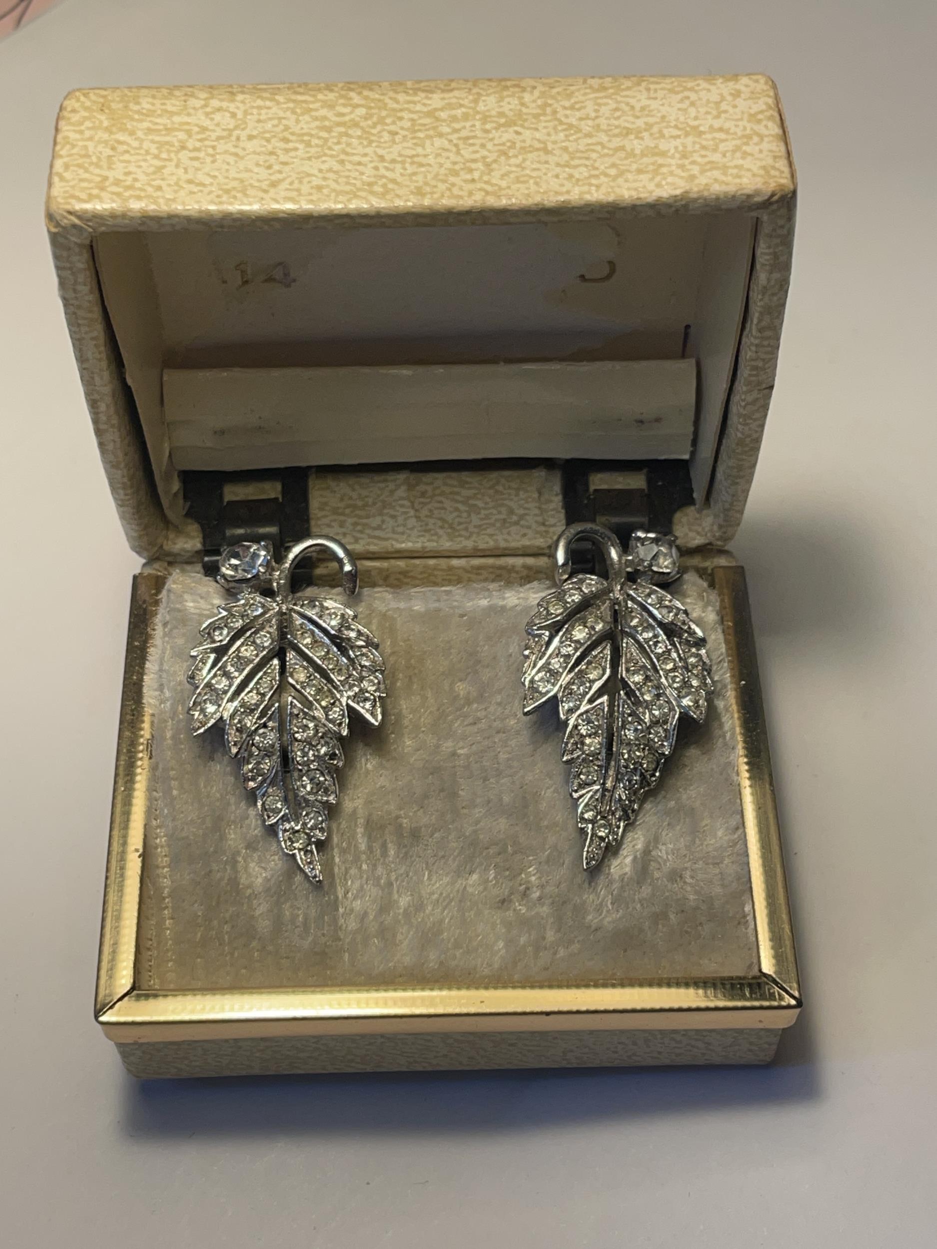 A PAIR OF 1040'S METAL RHODIUM AND CLEAR STONE EARRINGS IN A LEAF DESIGN WITH PRESENTATION BOX