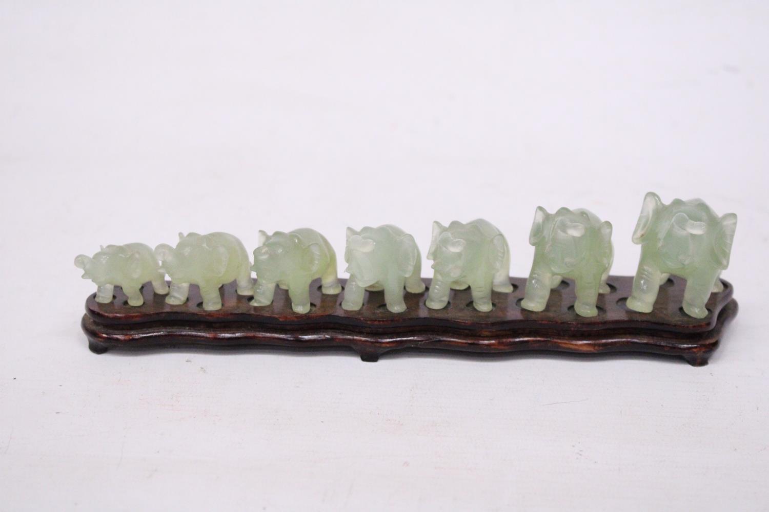 SEVEN GRADUATING JADE ELEPHANTS ON A WOODEN PLINTH (1 A/F)