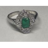 A WHITE METAL RING WITH A RECTANGULAR LABORATORY EMERALD SURROUNDED BY CLEAR STONES SIZE Q/R