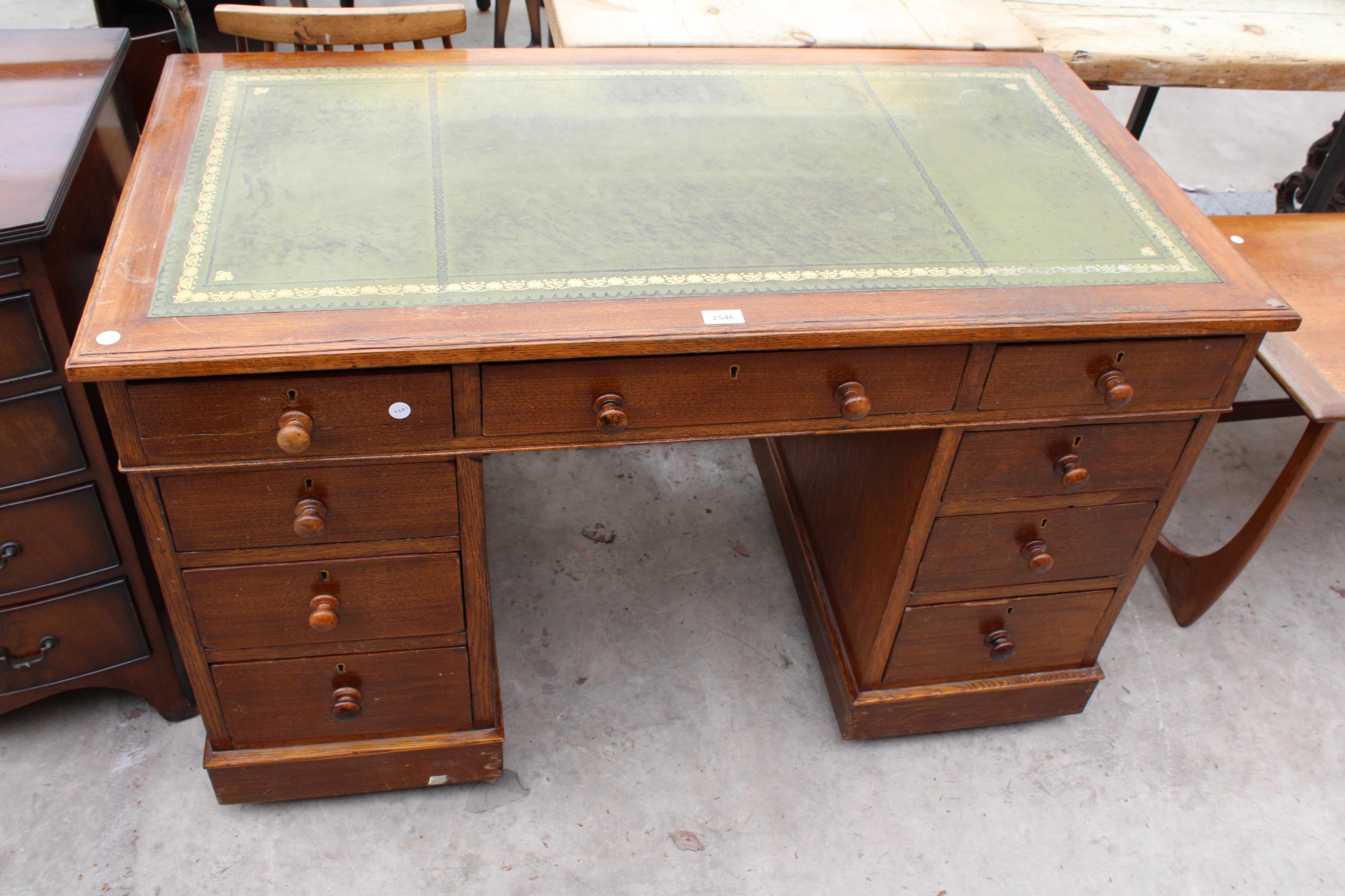 AN EDWARDIAN OAK TWIN-PEDESTAL DESK ENCLOSING NINE DRAWERS WITH INSET LEATHER TOP, 48" X 25"