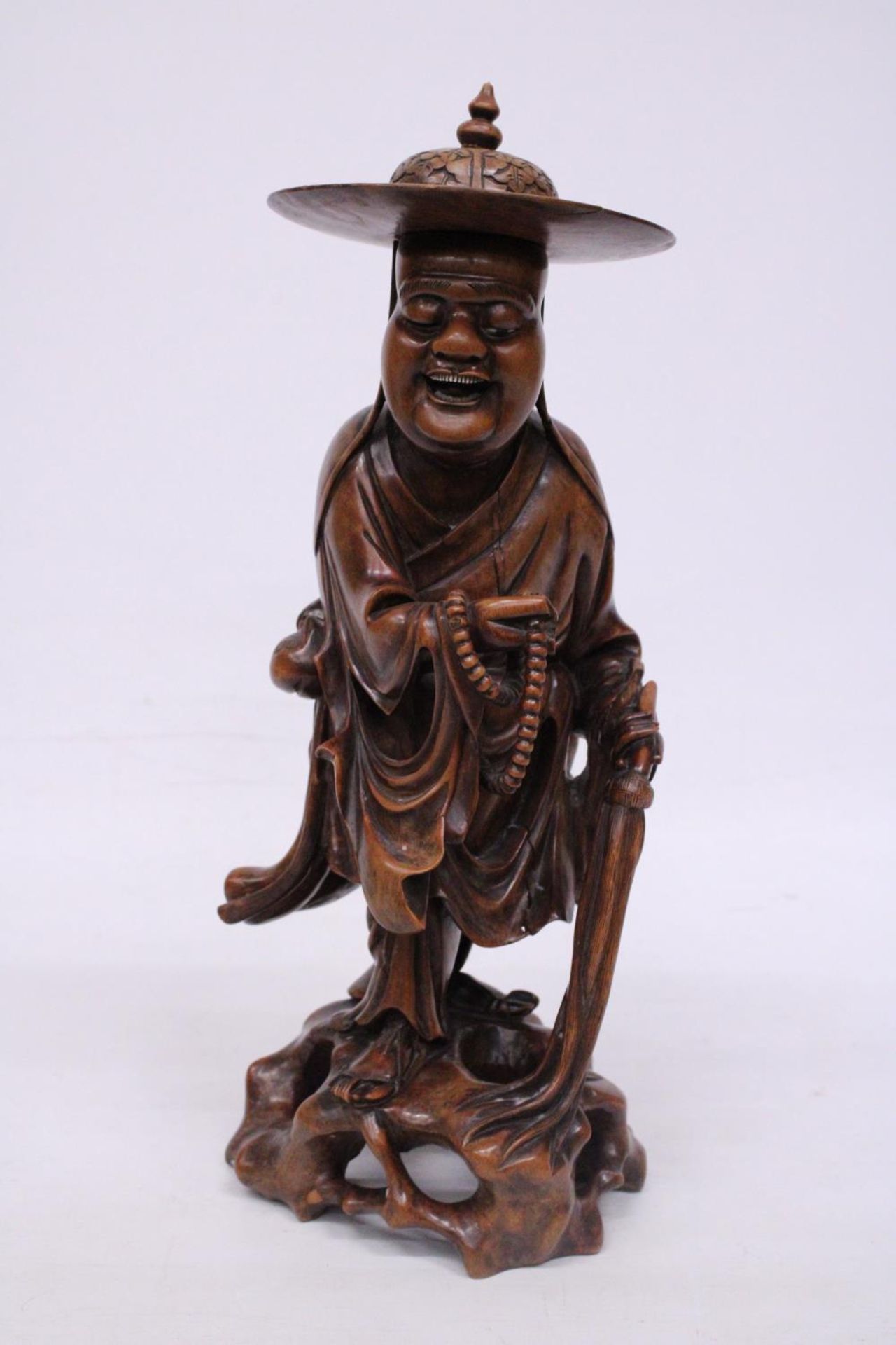 A VINTAGE ORIENTAL ROOTWOOD CARVING OF A HOLYMAN WEARING A TYPICAL COOLIE HAT WITH TEETH (