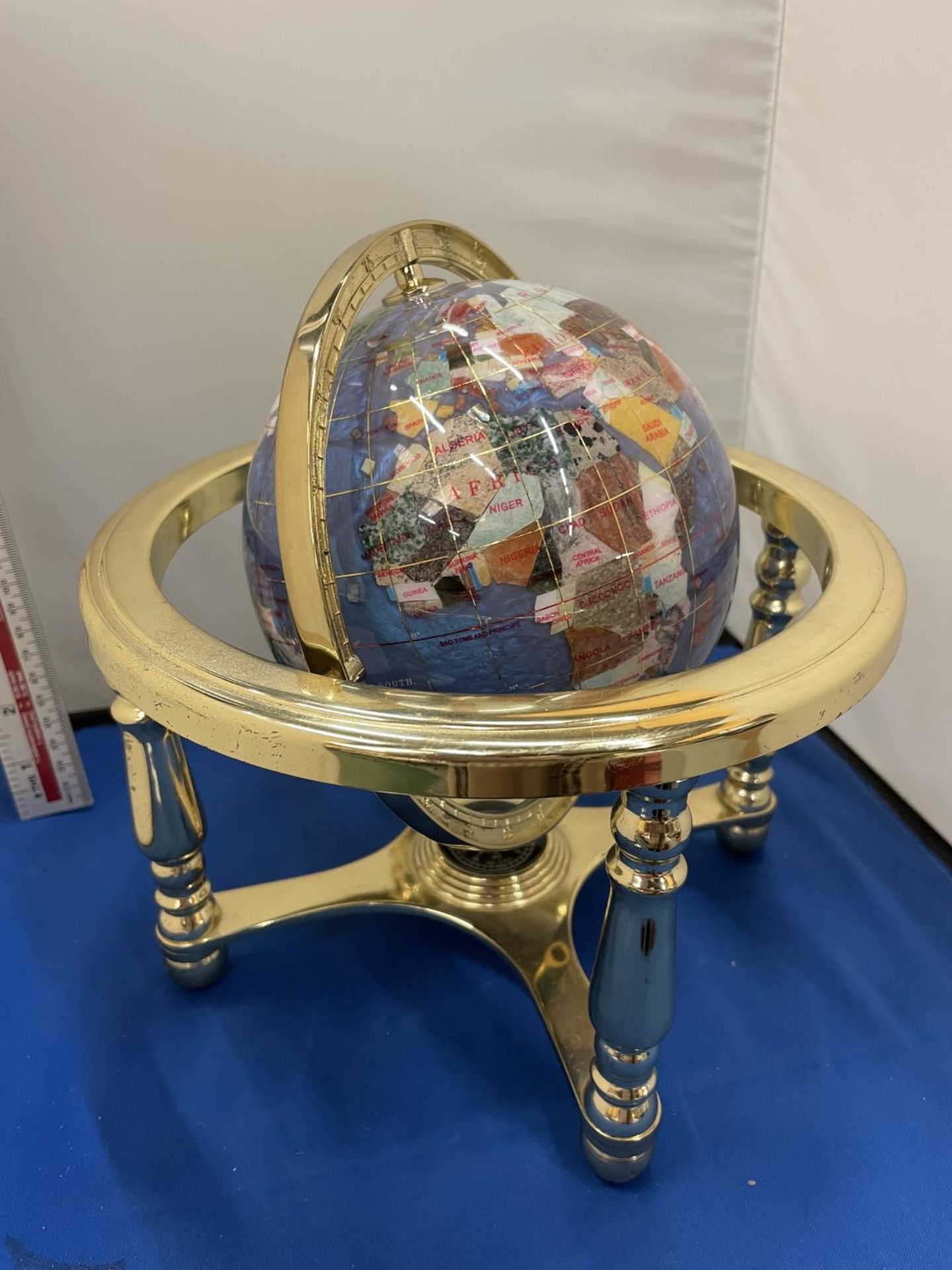 A GLOBE MADE UP OF SEMI PRECIOUS STONES ON A BRASS COLOURED BASE