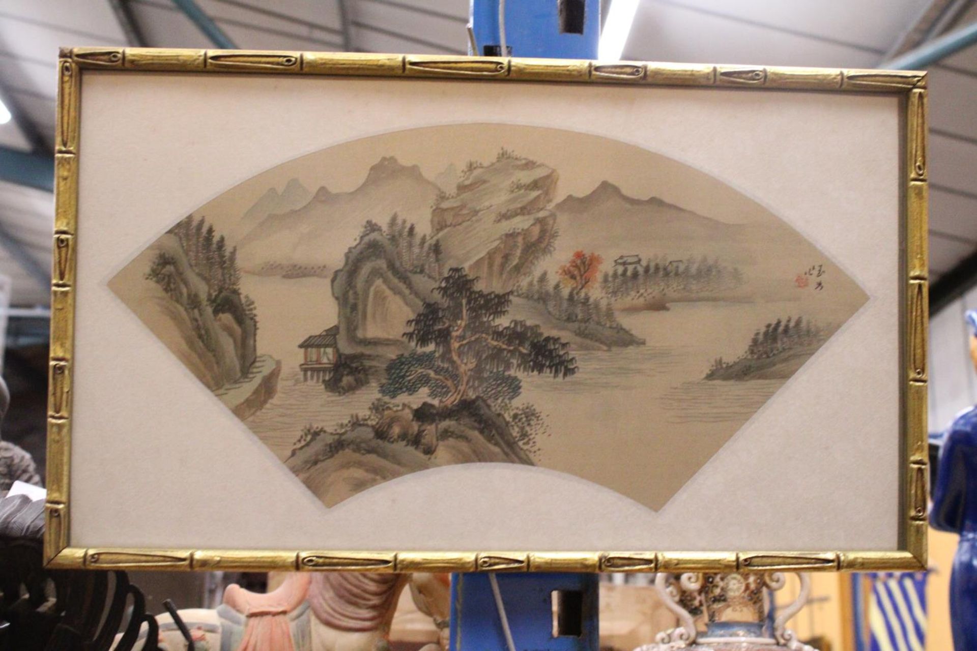 A CHINESE FAN PAINTING OF A LANDSCAPE IN BAMBOO FRAME - 49 X 29 CM