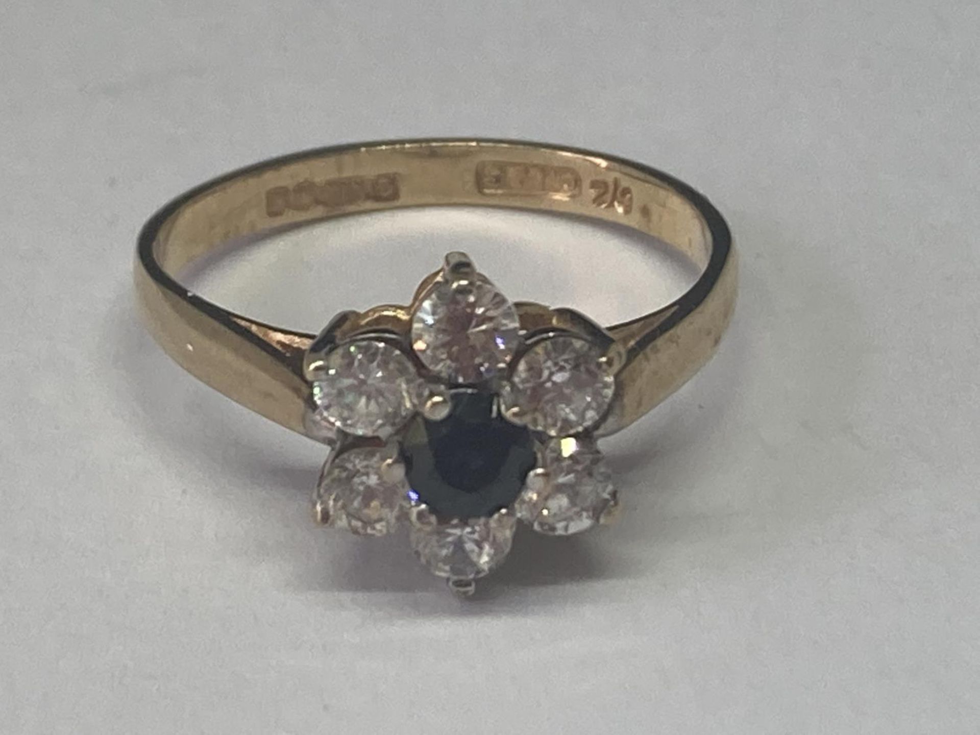 A 9 CARAT GOLD RING WITH A SAPPHIRE SURROUNDED BY CUBIC ZIRCONIAS SIZE N