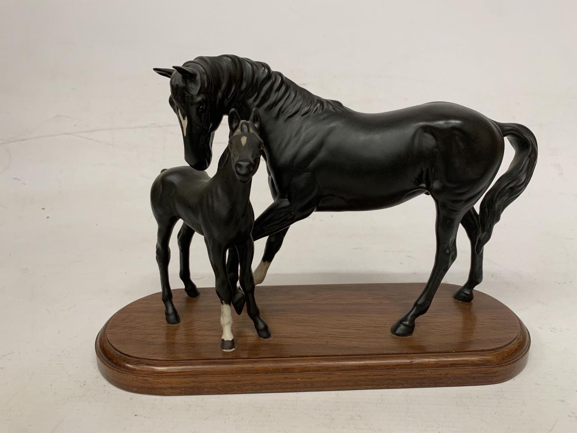 A FIGURE OF BLACK BEAUTY AND FOAL ON A WOODEN PLINTH