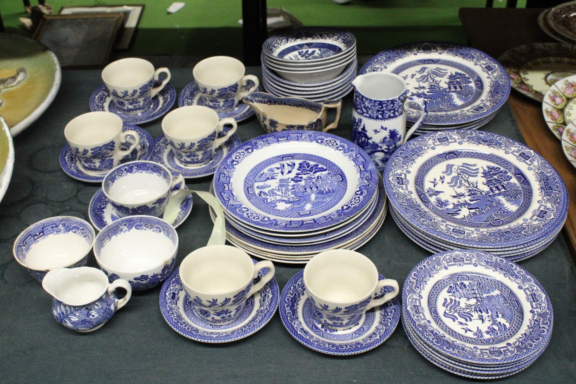 A QUANTITY OF BLUE AND WHITE WILLOW PATTERN DINNERWARE TO INCLUDE VARIOUS SIZES OF PLATES, BOWLS,