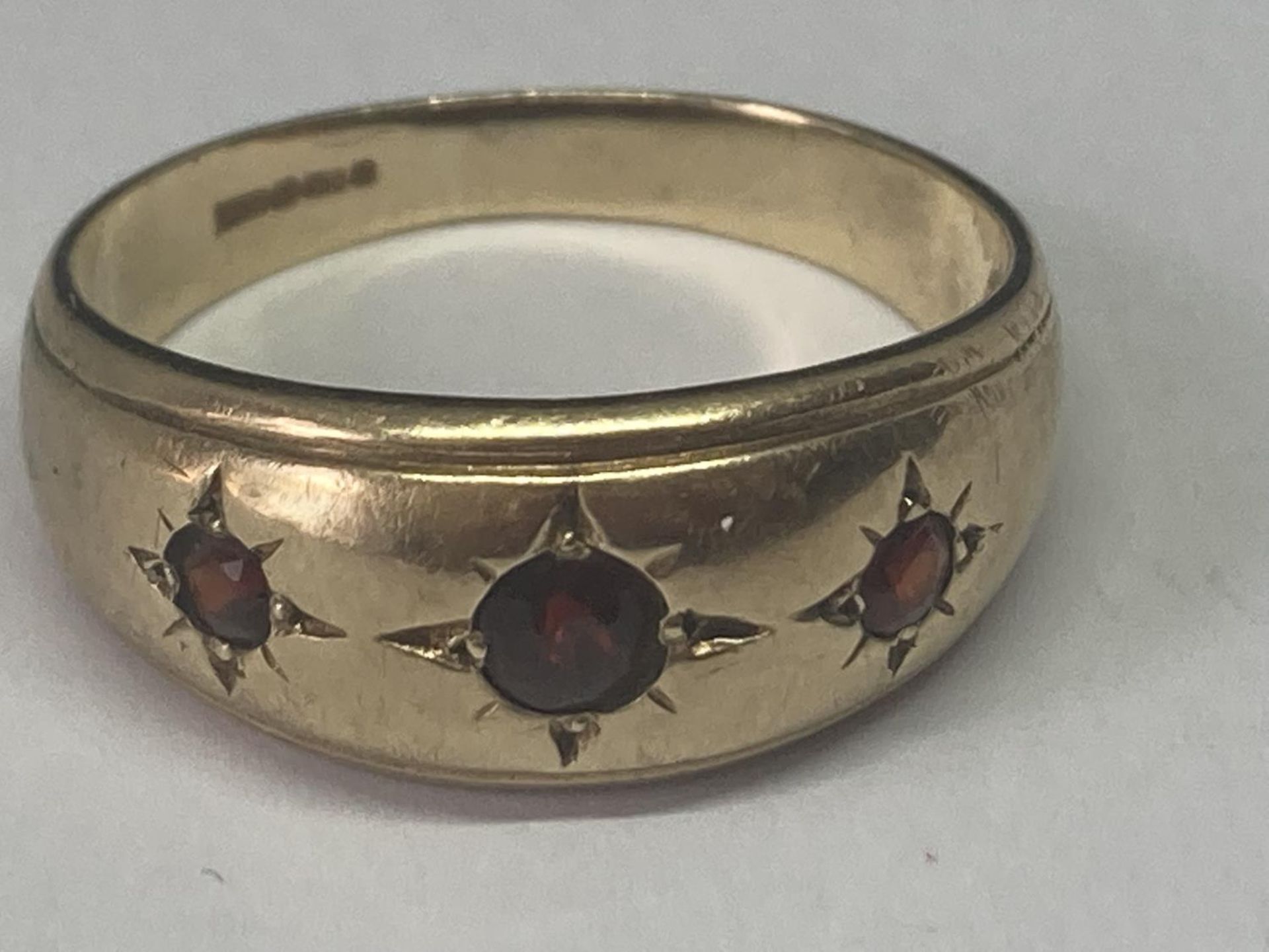 A 9 CARAT GOLD RING WITH THREE GARNETS SIZE V