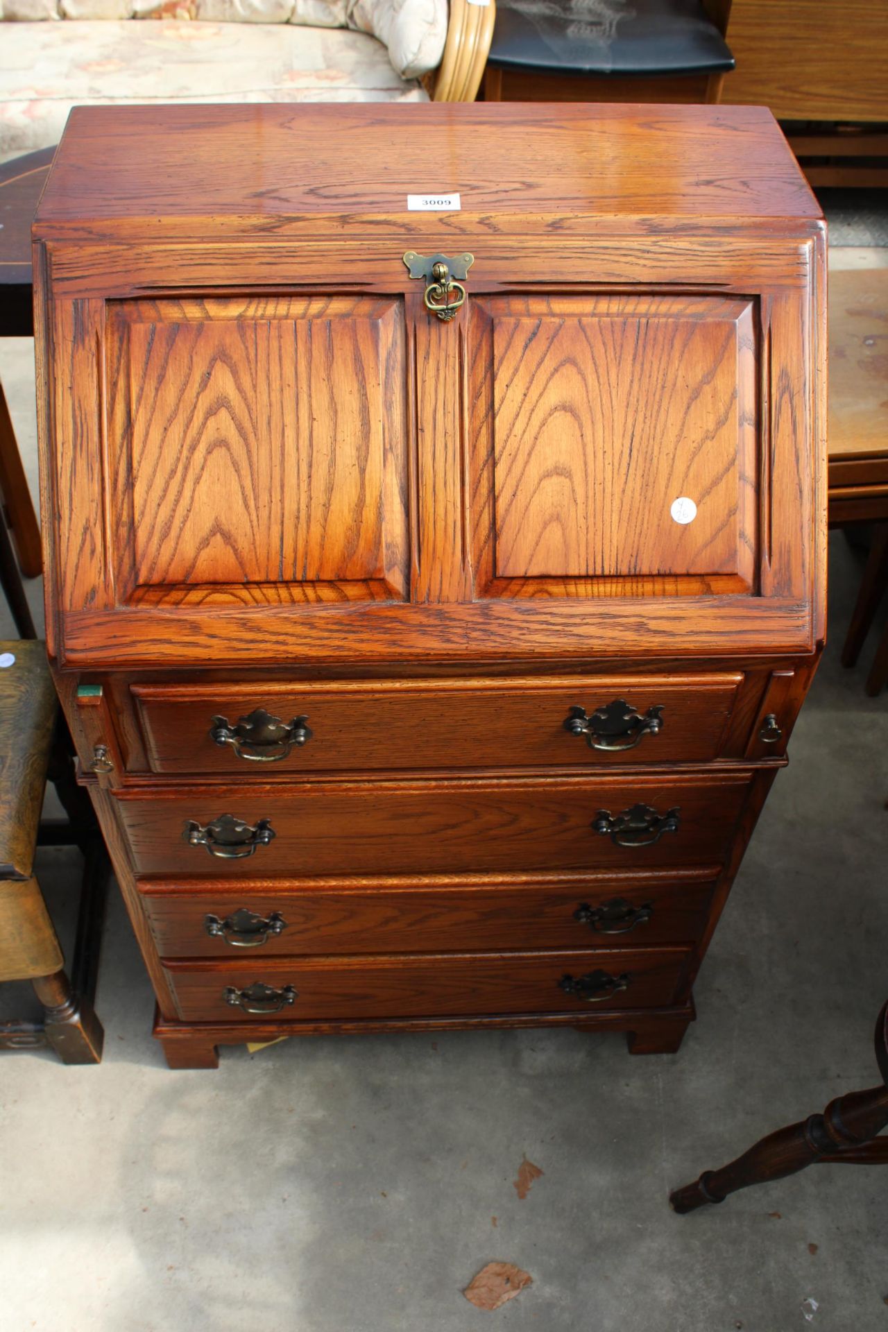 AN OAK REPRODUX BUREAU WITH FITTED INTERIOR, FOUR DRAWERS TO BASE ON BRACKET FEET, 23" WIDE