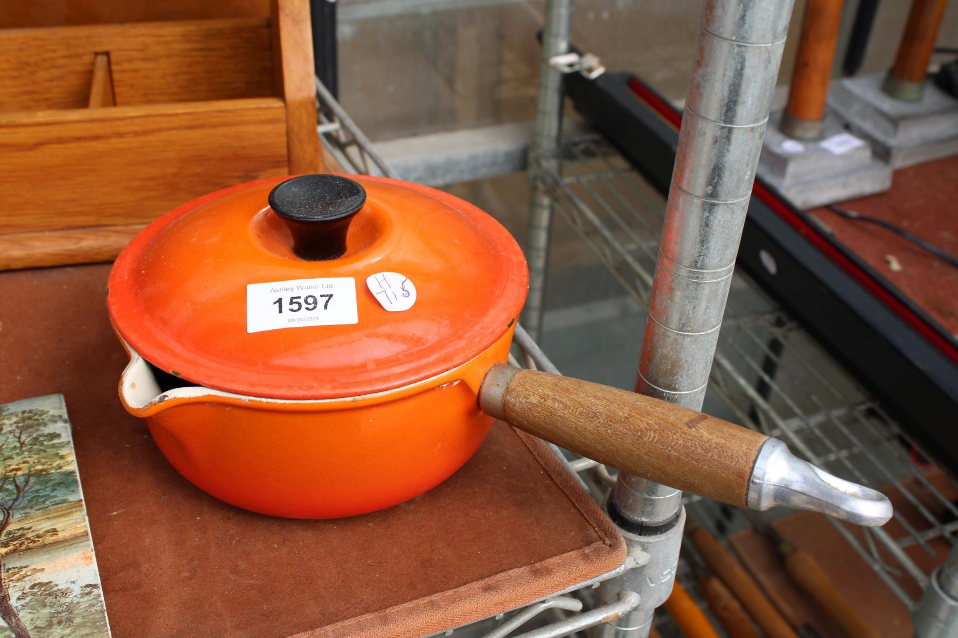 A SMALL ORANGE LE CREUSET PAN WITH LID