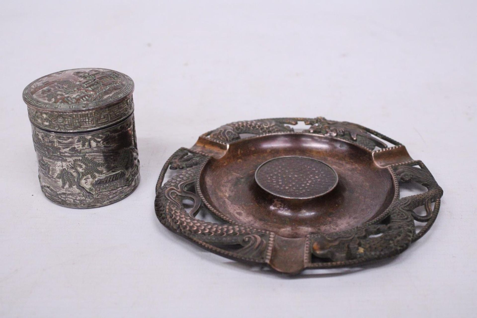 A VINTAGE (POSSIBLY BRONZE) ORIENTAL ASHTRAY WITH DRAGON DESIGN TOGETHER WITH A WHITE METAL LIDDED