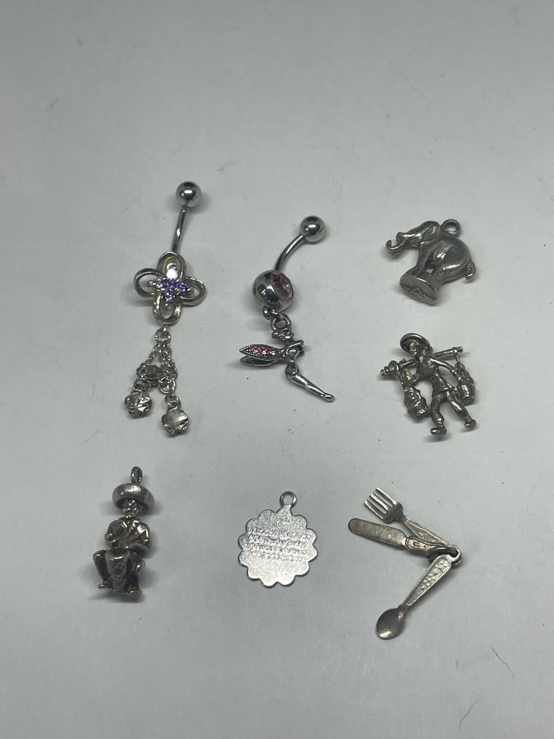 SEVEN SILVER ITEMS TO INCLUDE TWO BELLY BARS AND FIVE CHARMS