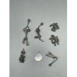 SEVEN SILVER ITEMS TO INCLUDE TWO BELLY BARS AND FIVE CHARMS