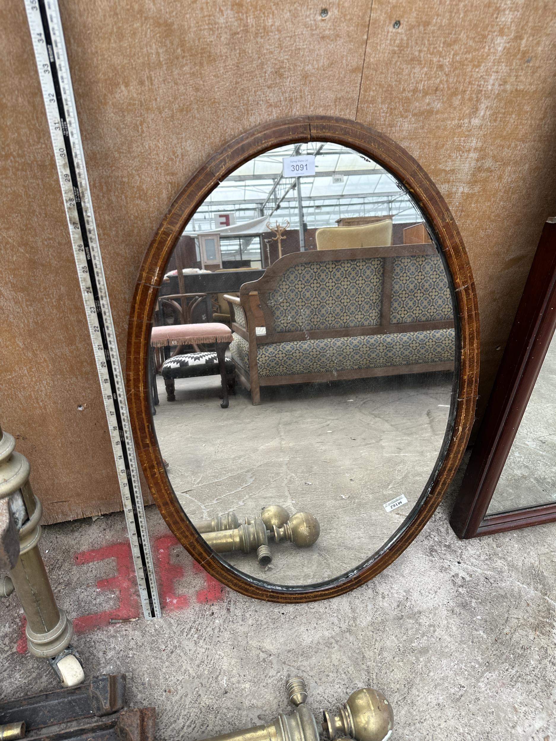 AN OVAL MAHOGANY MIRROR