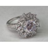 A WHITE METAL RING WITH 3 CARATS OF MOISSANITE IN A CLUSTER DESIGN SIZE Q