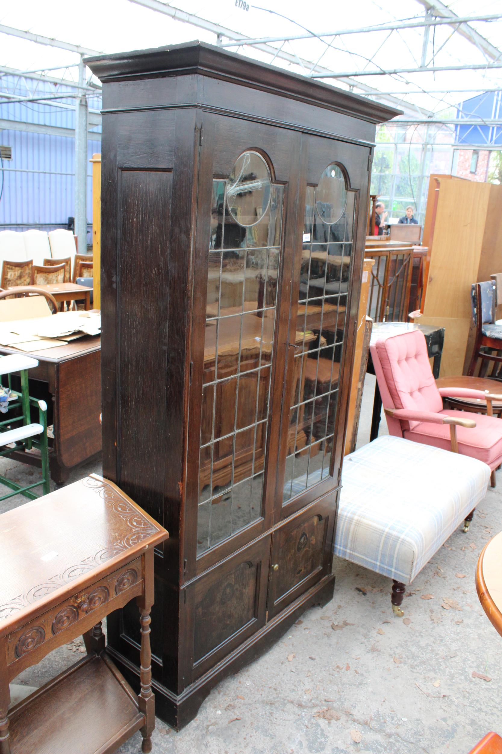 AN OAK ART NOUVEAU GLAZED AND LEADED TWO DOOR DISPLAY CABINET WITH CUPBOARDS TO BASE, 41" WIDE,