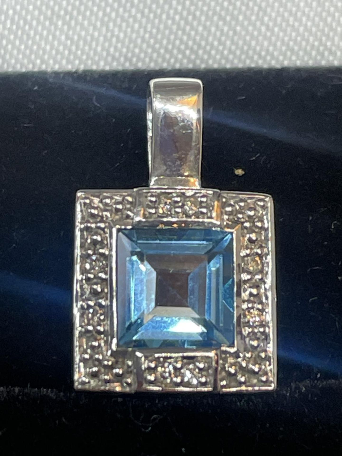 A 9 CARAT WHITE GOLD SQUARE PENDANT WITH CENTRE BLUE TOPAZ SURROUNDED BY DIAMONDS IN A - Image 2 of 5
