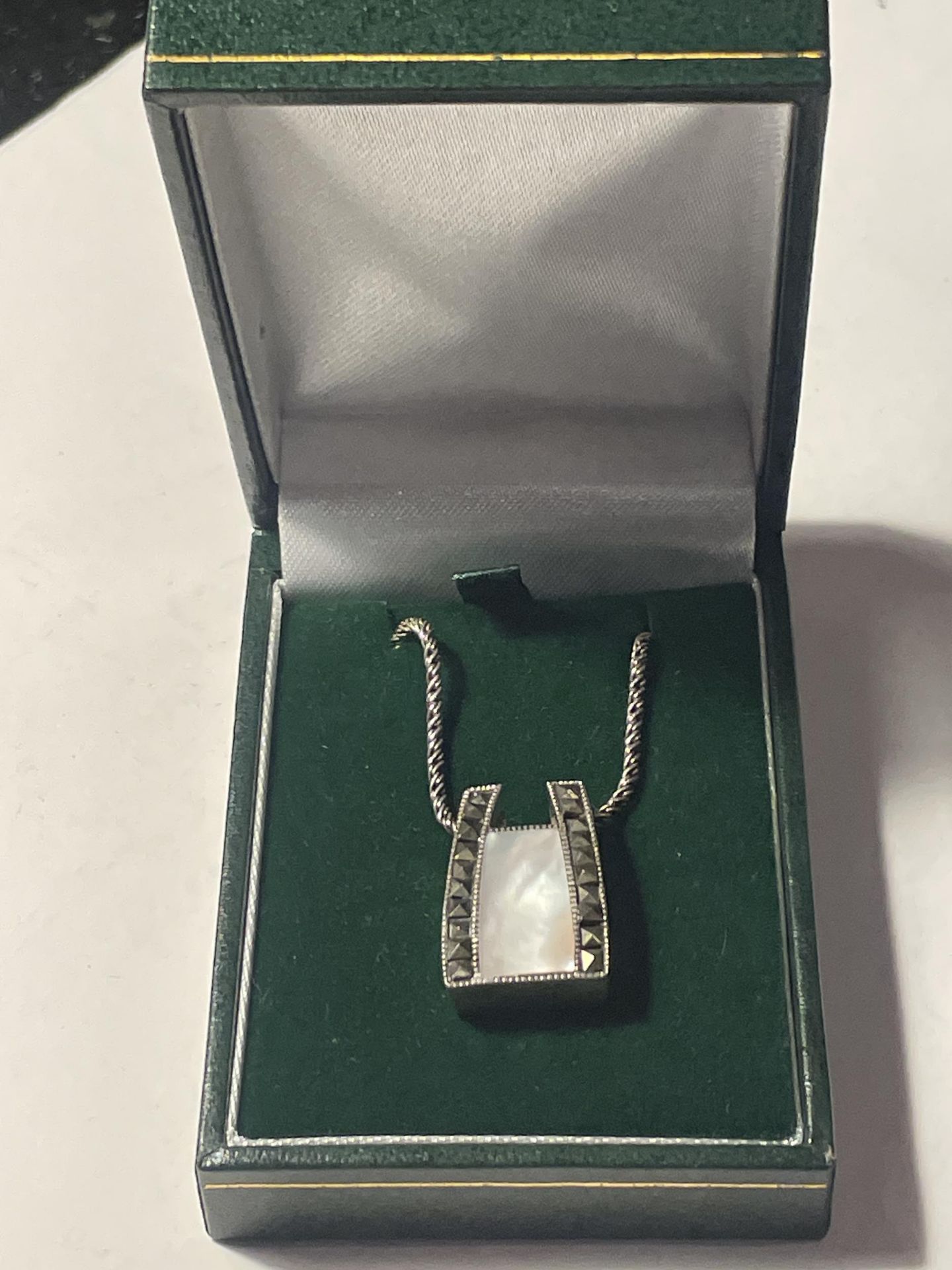 A SILVER NECKLACE WITH A MOTHER OF PEARL AND MARCASITE DECO STYLE PENDANT IN A PRESENTATION BOX