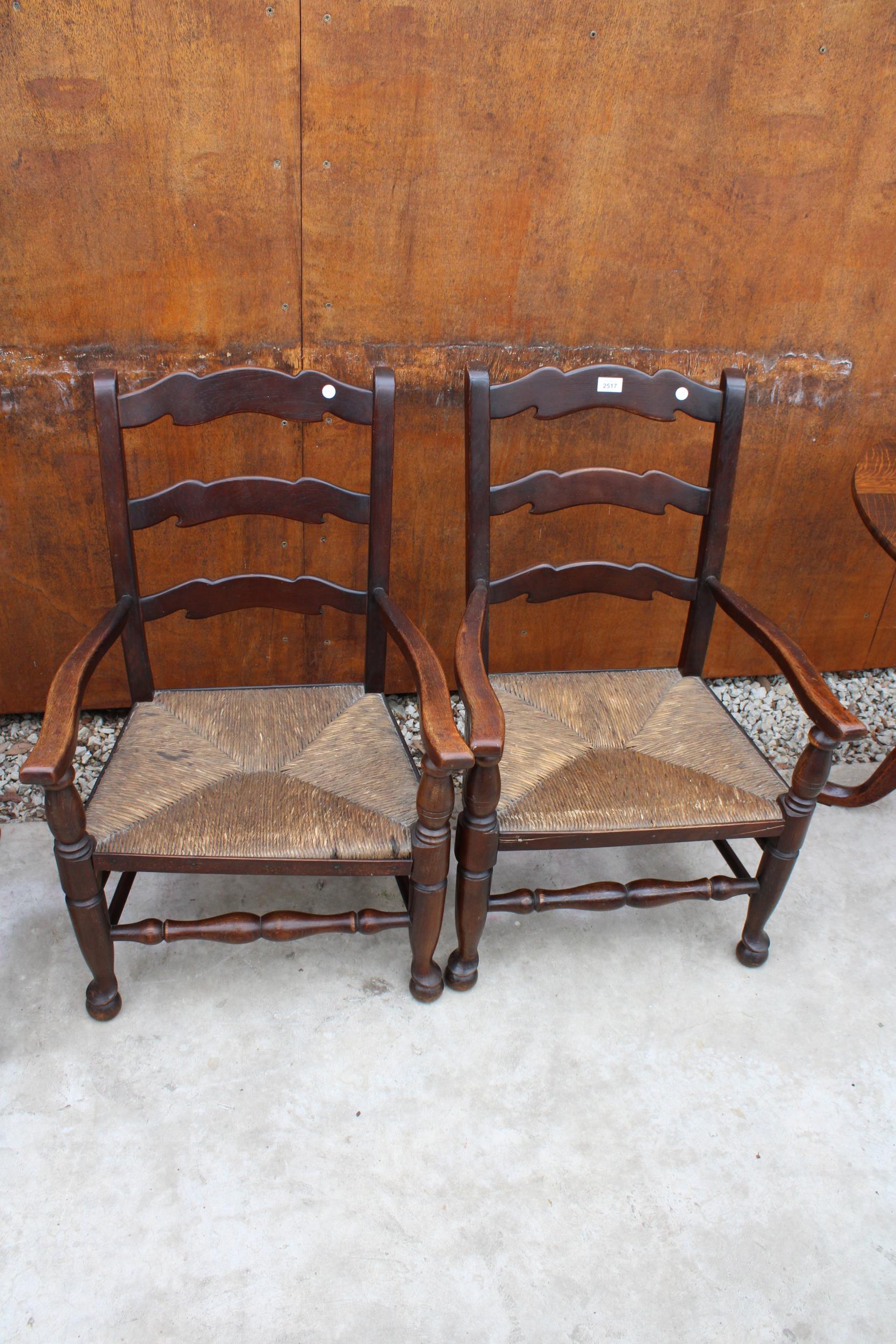 A PAIR OF 18TH CENTURY STYLE LOW OAK LADDER-BACK ELBOW CHAIRS WITH RUSH SEATS