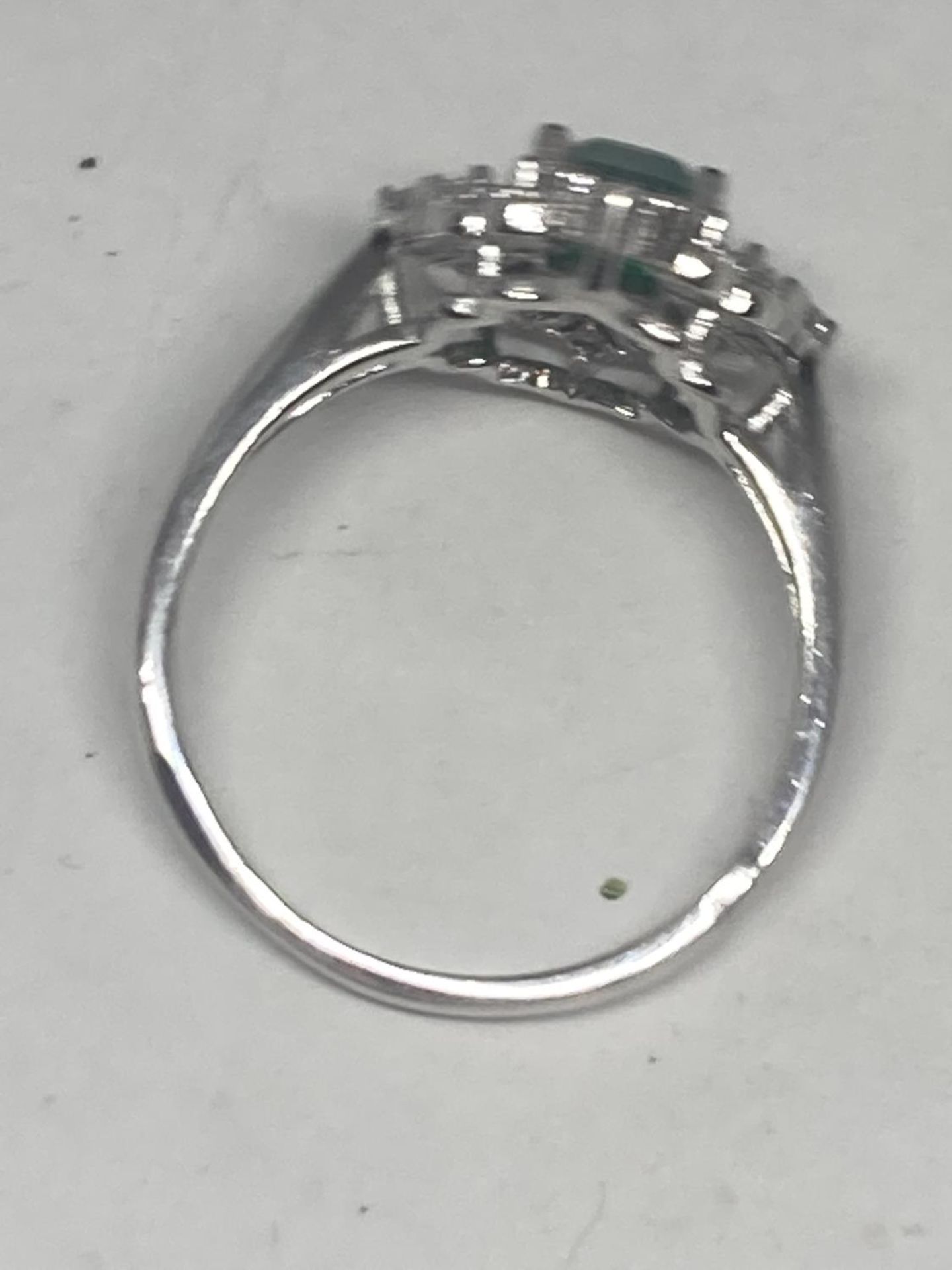 A WHITE METAL RING WITH A RECTANGULAR LABORATORY EMERALD SURROUNDED BY CLEAR STONES SIZE Q/R - Image 5 of 8